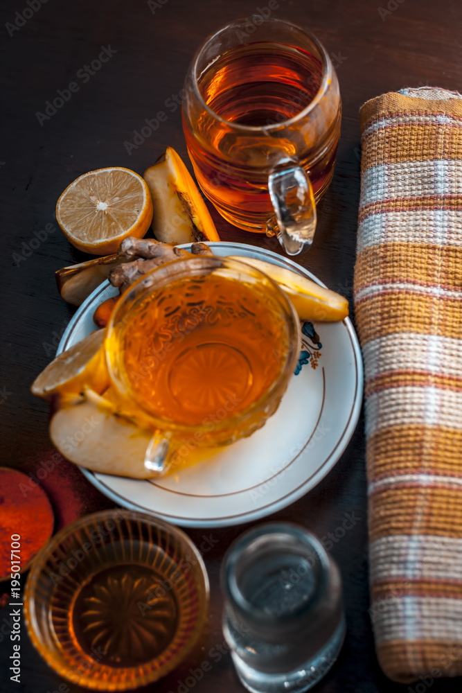 Φωτογραφία Close up of a herbal tea  consisting of apple juice,lemon,ginger and warm water in a transparent cup on a wooden surface in dark Gothic colors