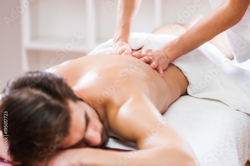 Young man is enjoying massage on spa treatment. 