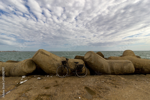 bicicletta su molo con scogli davanti al mare 