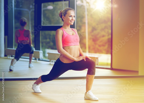 smiling woman stretching leg in gym