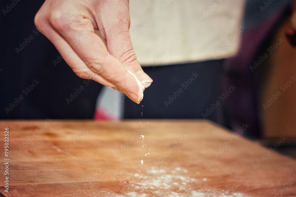 Chef pouring flour on wooden board.Selective focus.