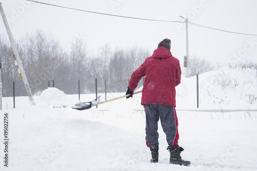 A person removes snow on the plot of land. A snowstorm on the street.