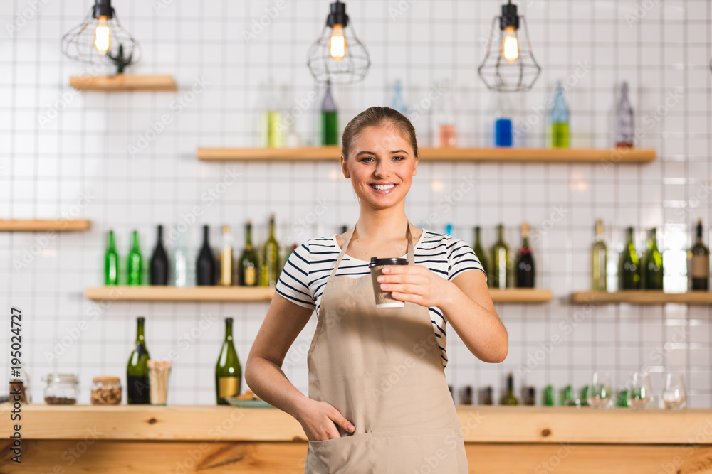 Positive female barista holding a plastic cup Positive female barista holding a plastic cup