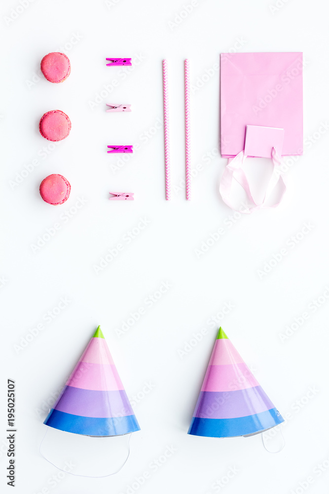 Birthday party accessories. Party hat, sweets, paper bag for gift on white background top view copy space pattern