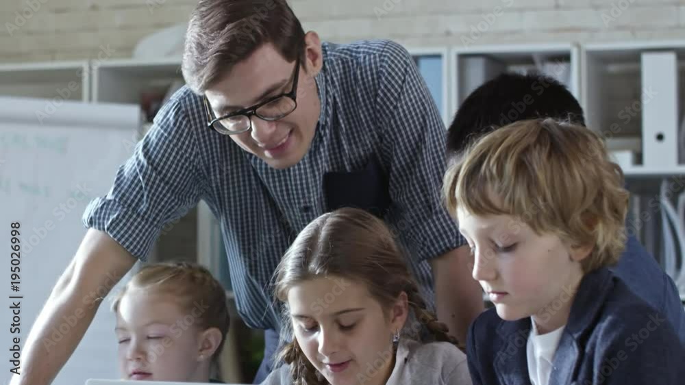 Four primary school children working together on laptop computer during ...