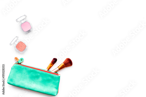 Decorative cosmetics background. Eyeshadow, brushes in cosmetic bag on white top view copy space