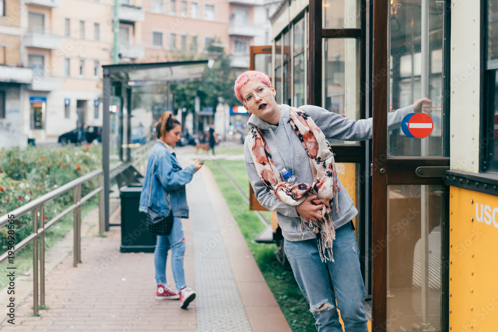 young woman pink hair outdoors getting off tram - transport, commuting, traveller concept