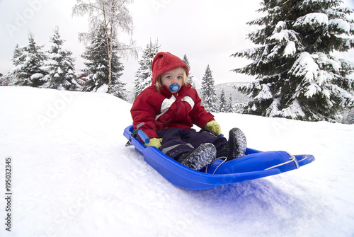 Tela Child cute girl sitting on baby bob sled in winter forest