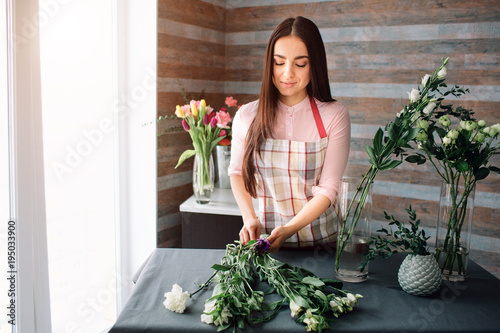 Fototapet Female florist at work: pretty young dark-haired woman making fashion modern bouquet of different flowers