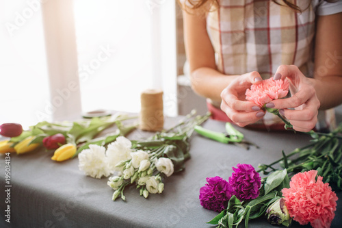 Female florist at work: pretty young dark-haired woman making fashion modern bouquet of different flowers. Women working with flowers in workshop © estradaanton