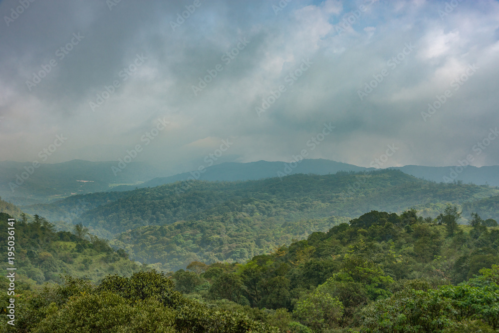 Talakaveri, India - October 31, 2013: Blue and gray clouds over the green jungle covered highlands around the spring of the Kaveri River sanctuary.