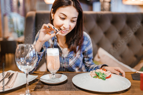 Eastern woman eating spaghetti pasta with fork in luxury restaurant