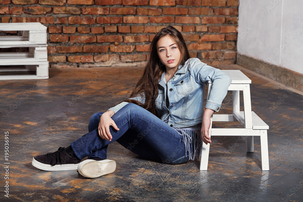 Pretty Teenager Girl In Casual Clothes Sitting By A Wooden Wall