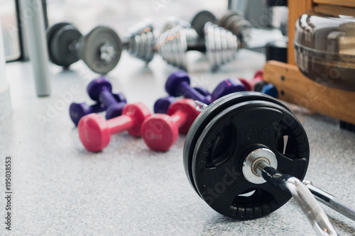 set of equipment for weightlifting and fitness: dumbbells, barbell and rowing machine at gym