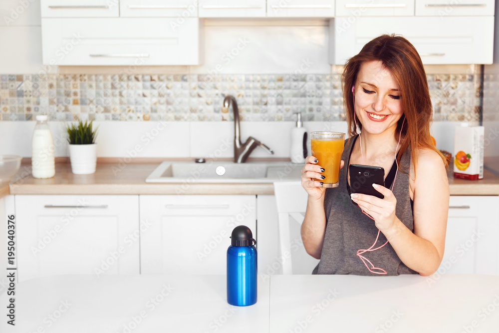 Smiling woman with smartphone and orange juicein the kitchen Smiling woman with smartphone and orange juicein the kitchen