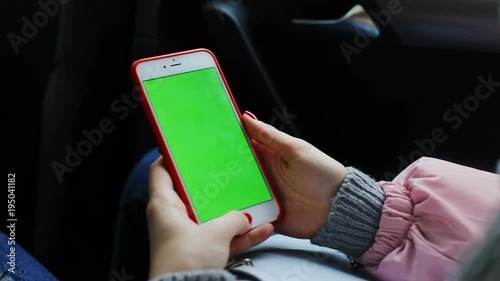 woman hand using smart phone mobile in the car / green screen chromakey mockup closeup taxi cab pasanger app notification pay system traveling female touchscreen busy business trip internet online 3g photo