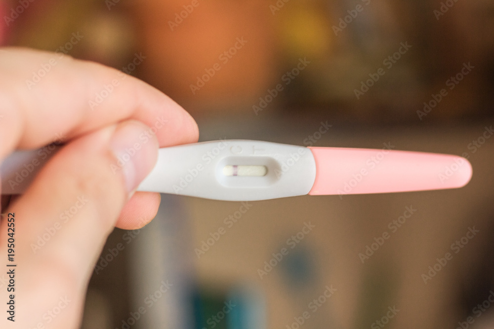 Human hand holds a negative pregnancy test.