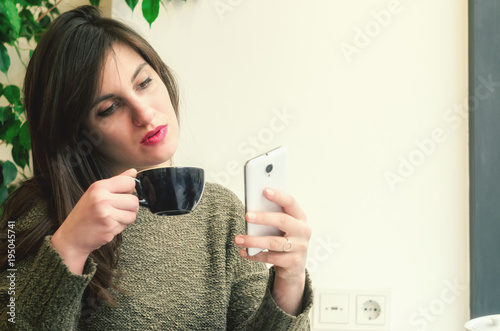 Beautifur girl using smartphone and drinking coffee