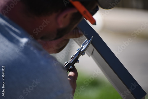 Man cutting metal with tin snips.