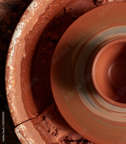 production process of pottery. mug of red clay on a potter's wheel.