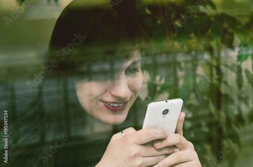 Cafe city lifestyle woman on phone texting text message on smartphone app sitting indoor in trendy urban cafe. Caucasian female model