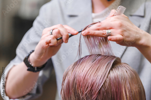 Close-up of a hairdresser woman cutting hair in beauty salon