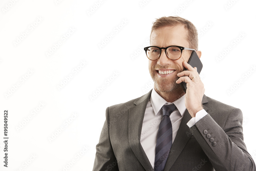 Businessman with handy.Portrait of happy mature business man wearing suit and using mobile phone while talking with somebody. Businessman with handy.Portrait of happy mature business man wearing suit and using mobile phone while talking with somebody.