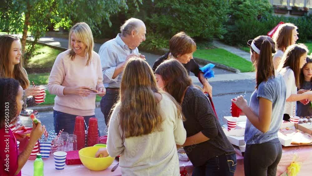 Neighbours stand talking and eating at a block party