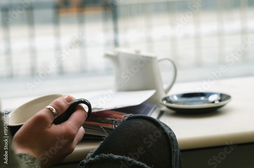 Young Woman Enjoying her coffee or tea in cafe, Looking Out the Window on streets of city .