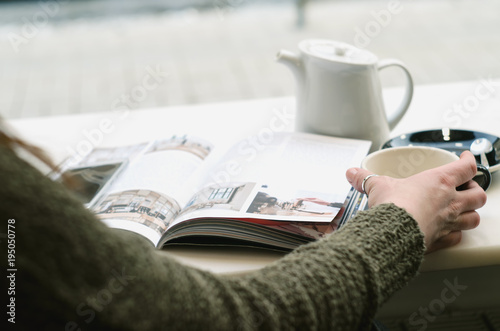 Young Woman Enjoying her coffee or tea in cafe, Looking Out the Window on streets of city .