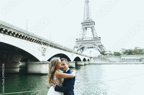 Luxury wedding couple poses before river Seine and the Eiffel Tower somewhere in Paris © syrotkin