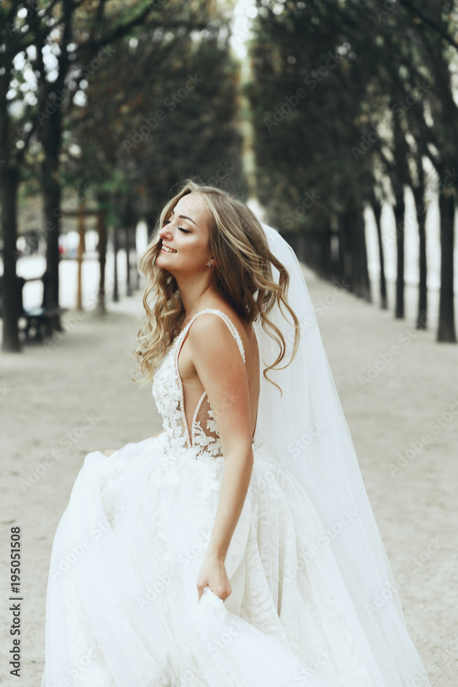 Mysterious and happy bride whirls between the trees somewhere in Paris