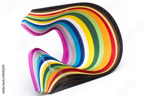 A stack of multicolored quilling paper stripes forming a wired futuristic shape on white background.