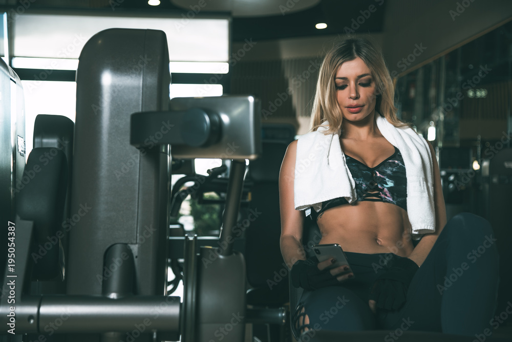 woman resting using mobile phone with towel in the gym woman resting using mobile phone with towel in the gym