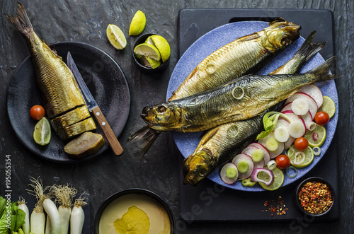 Photography Mediterranean food, smoked Herring fish served with green onion,lemon,cherry tomatoes,spices,bread and Tahini sauce on dark background