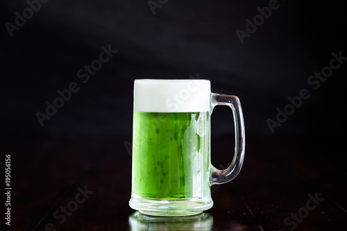 A stein beer mug with green beer on rustic wood table.