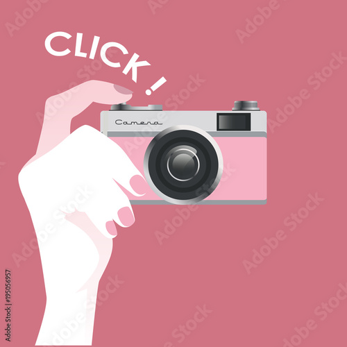 Cute vintage style pink photo camera, held by a female hand, isolated on pink background.