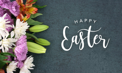 Spring season still life with Happy Easter calligraphy holiday script over dark blackboard background texture with beautiful colorful white, pink, orange, purple and green flower blossom bouquet