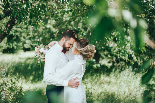 stylish groom with a beard and groom in the garden. fine art style. rustic photo
