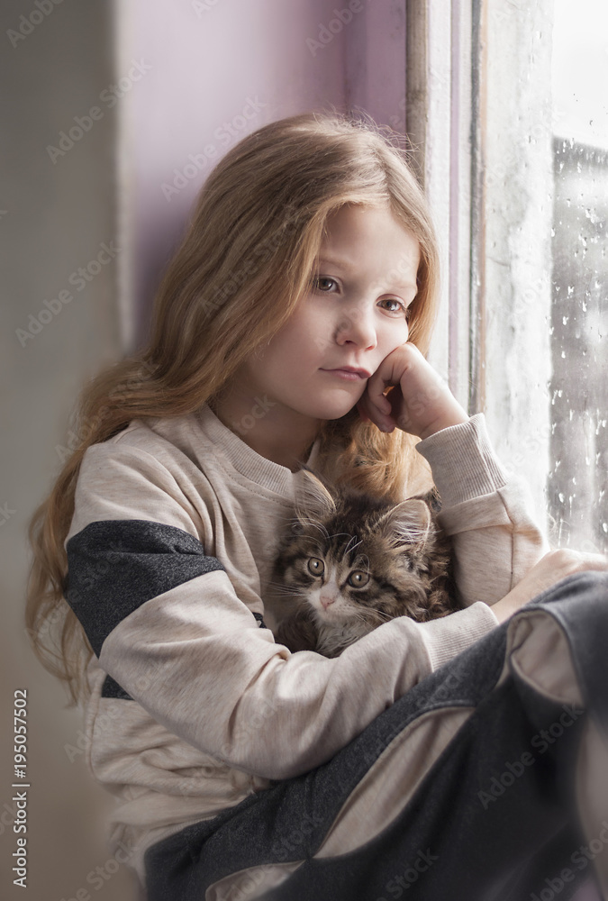Cute little girl sitting by the window with fluffy cat Cute little girl sitting by the window with fluffy cat