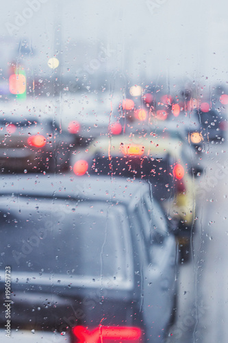 Rain drops close up on car window. Traffic jam motion blur