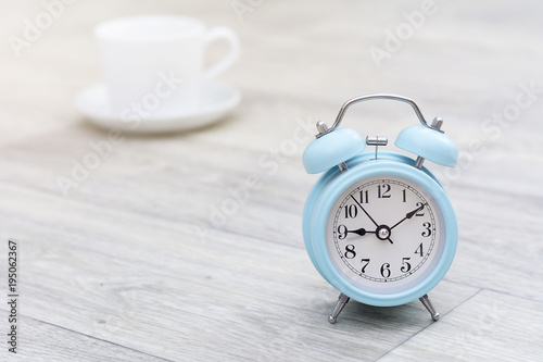 Blue alarm clock in morning light and coffee, morning concept photo