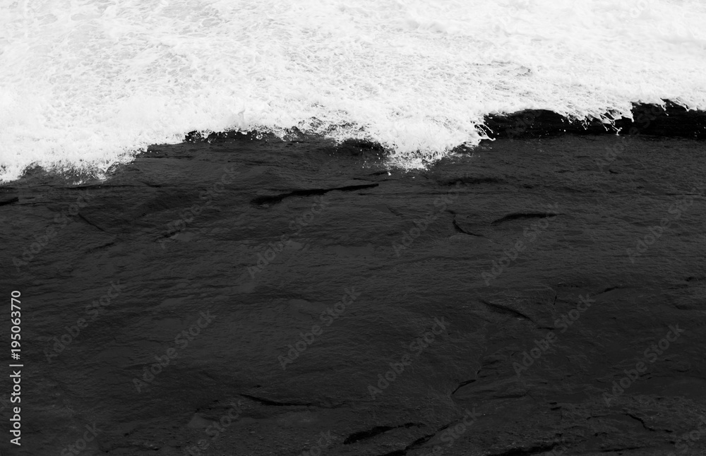 texture of dark stones contrasting with white foam of the waves
