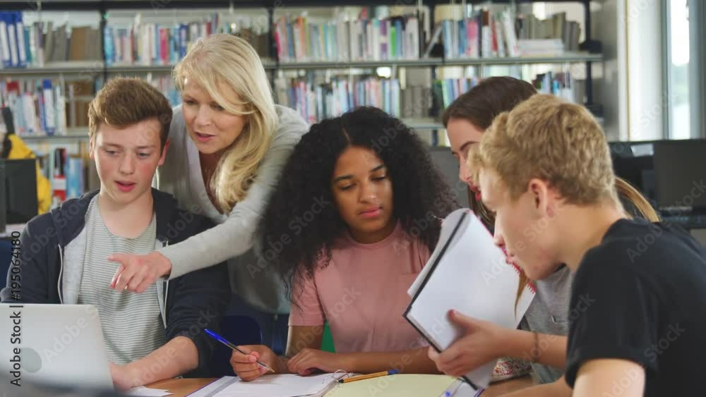 Female Teacher Working With College Students In Library Female Teacher Working With College Students In Library