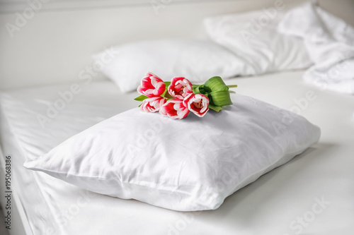 Soft pillow with tulips on bed
