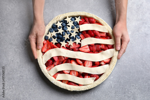 Woman with American flag pie on grey background