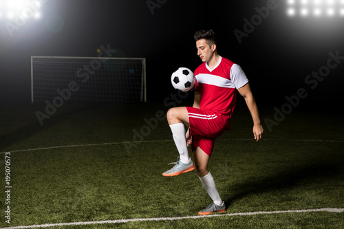 Soccer player juggling football on field