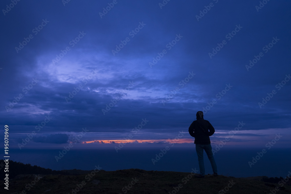 Man looking at the sea at dusk on Mount Jaizkibel, Basque Country