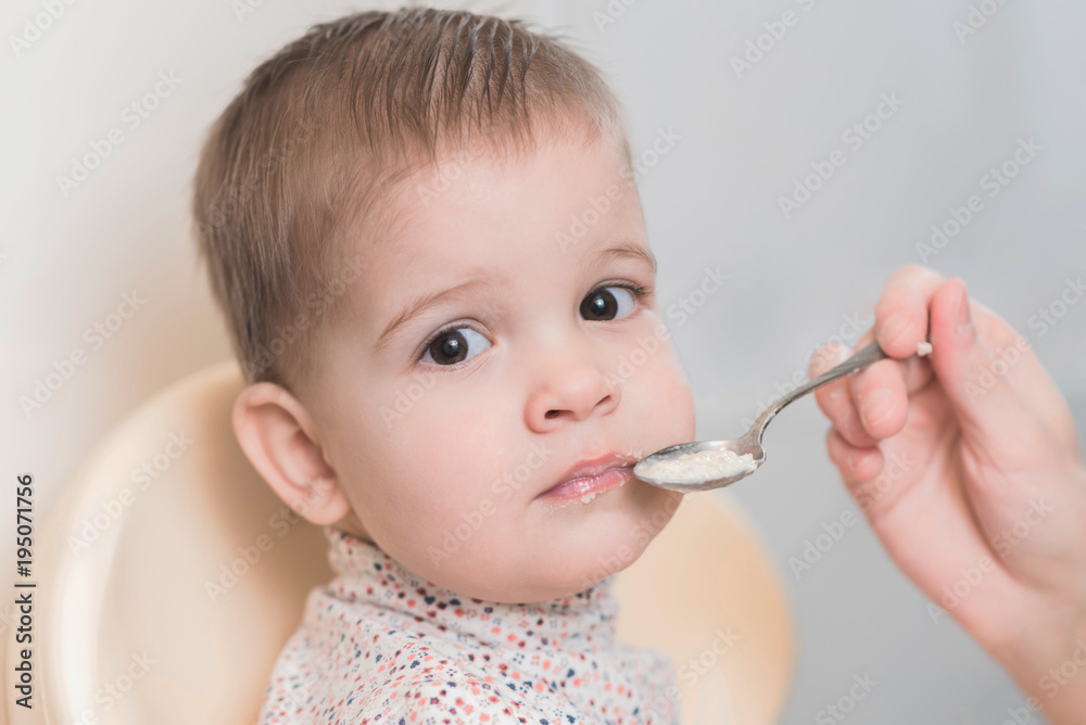 mom in the kitchen is feeding the baby milk porridge mom in the kitchen is feeding the baby milk porridge