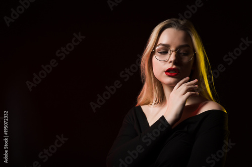 Lovely young woman wearing glasses and trendy blouse, posing in the shadow